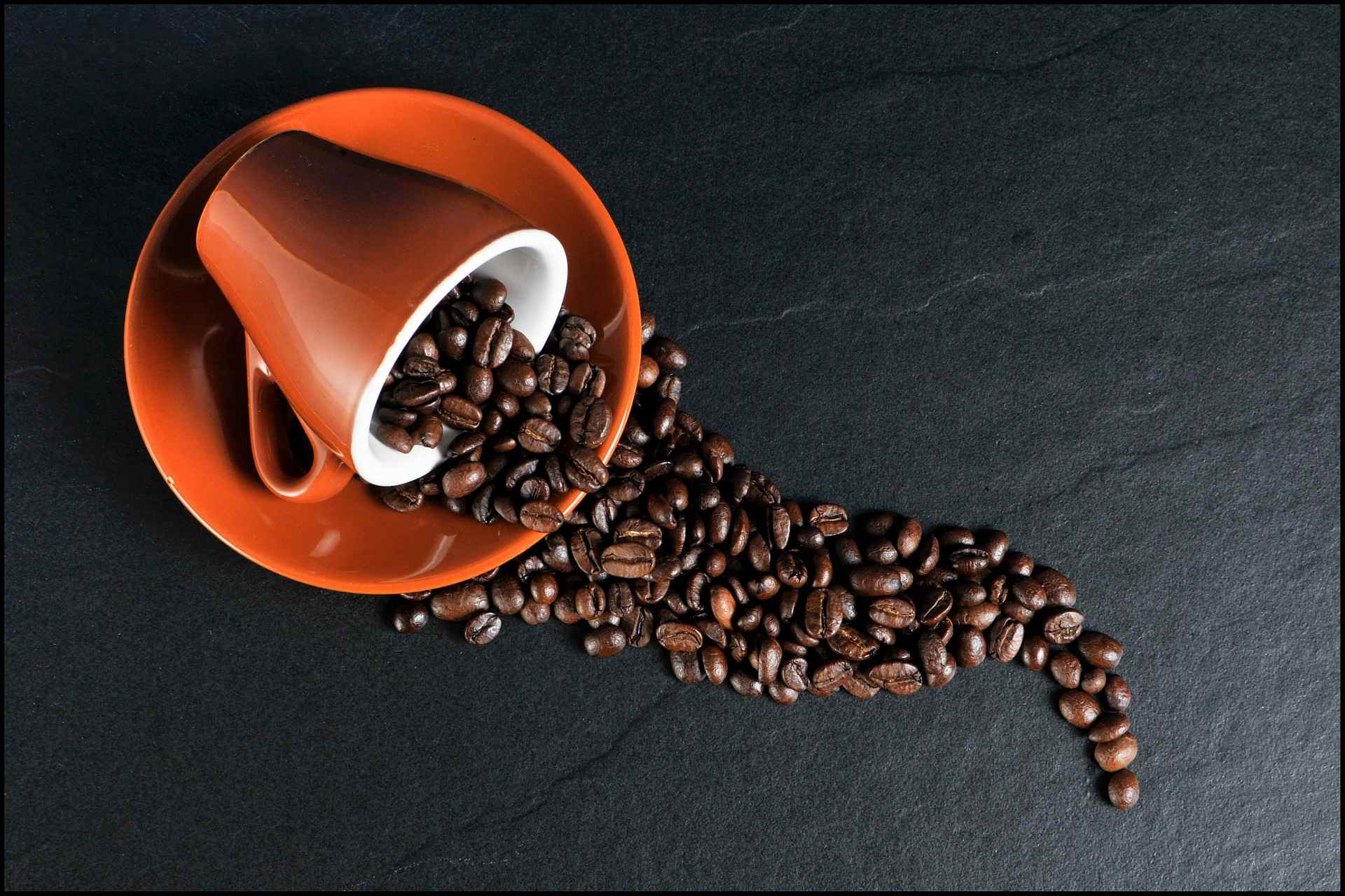 Kaffeebohnen kullern aus einer Tasse