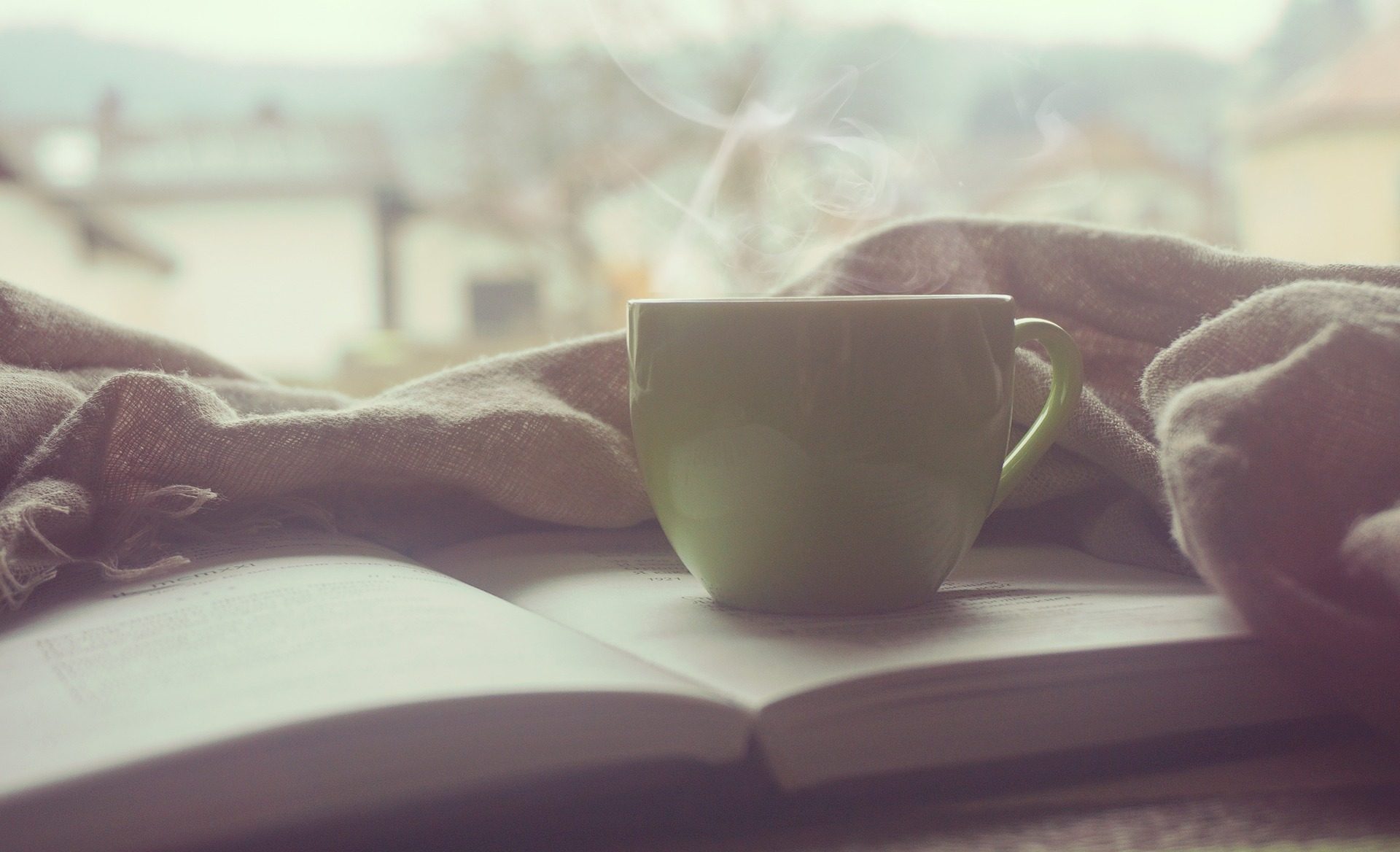Eine Tasse Kaffee steht auf einem aufgeschlagenen Buch